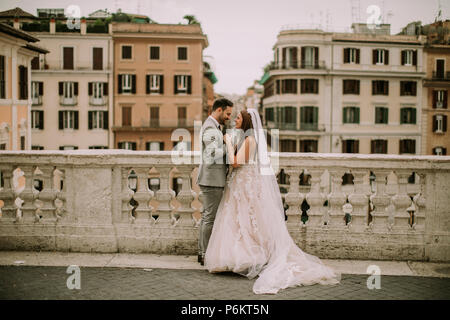 Young attractive couple nouvellement marié la marche et posant dans Rome avec belle architecture ancienne et sur l'arrière-plan le jour de leur mariage Banque D'Images