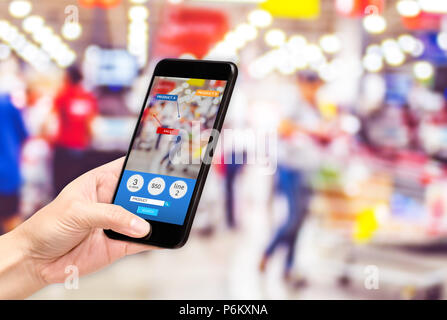 Tenir la main et téléphone mobile utilisant la réalité augmentée (AR) l'app pour voir promotion vente en supermarché store,Digital Lifestyle Technologie concept Banque D'Images