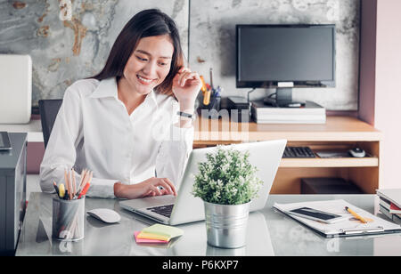 Asie businesswoman looking at laptop computer et visage souriant et de repos avec des professionnels de l'émotion à partir de la bonne nouvelle de la réussite commerciale dans l'accueil Banque D'Images