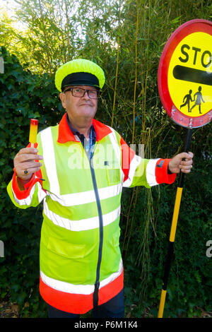 Iollipop homme qui vient de terminer son quart de travail à l'école crossing passage piétons. Il est en cours de refroidissement avec une sucette qui est la même couleur que sa tenue. Angleterre, Royaume-Uni Banque D'Images