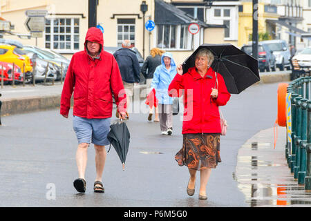 La ville de Sidmouth, Devon, UK. 1er juillet 2018. Météo britannique. Les visiteurs de la station balnéaire de Sidmouth dans le Devon avec parasols jusqu'à la ville attrape le bord d'une adoption forte pluie douche. Crédit photo : Graham Hunt/Alamy Live News Banque D'Images
