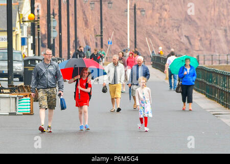 La ville de Sidmouth, Devon, UK. 1er juillet 2018. Météo britannique. Les visiteurs de la station balnéaire de Sidmouth dans le Devon avec parasols jusqu'à la ville attrape le bord d'une adoption forte pluie douche. Crédit photo : Graham Hunt/Alamy Live News Banque D'Images