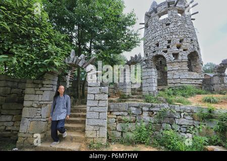 (180701) -- GUIYANG, 1 juillet 2018 (Xinhua) -- Chanson Peilun est vue à son château de pierre' dans 'Yelang Leping Village de Huaxi District à Guiyang, dans la province du Guizhou en Chine du sud-ouest, 1 juillet 2018. Chanson a renoncé à l'occasion de demeurer aux États-Unis en tant que caricaturiste. Au lieu de cela, il est retourné à une parcelle de terre en friche dans sa province de Guizhou. Là, il a décidé de créer un genre différent d'art. Le parc du château sont le foyer de plus de 300 statues bordant les deux côtés d'un ruisseau. Elles ressemblent à l'énorme des personnages humains sur l'île de Pâques. Chanson s'inspire de l'opéra local, une tradition Nuo i Banque D'Images