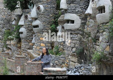 (180701) -- GUIYANG, 1 juillet 2018 (Xinhua) -- Chanson Peilun est vue à son château de pierre' dans 'Yelang Leping Village de Huaxi District à Guiyang, dans la province du Guizhou en Chine du sud-ouest, 1 juillet 2018. Chanson a renoncé à l'occasion de demeurer aux États-Unis en tant que caricaturiste. Au lieu de cela, il est retourné à une parcelle de terre en friche dans sa province de Guizhou. Là, il a décidé de créer un genre différent d'art. Le parc du château sont le foyer de plus de 300 statues bordant les deux côtés d'un ruisseau. Elles ressemblent à l'énorme des personnages humains sur l'île de Pâques. Chanson s'inspire de l'opéra local, une tradition Nuo i Banque D'Images