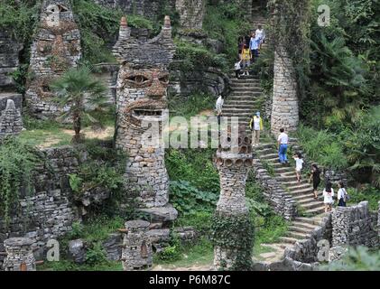 (180701) -- GUIYANG, 1 juillet 2018 (Xinhua) -- Les touristes visiter le château en pierre chanson Peilun' dans 'Yelang Leping Village de Huaxi District à Guiyang, dans la province du Guizhou en Chine du sud-ouest, 1 juillet 2018. Chanson a renoncé à l'occasion de demeurer aux États-Unis en tant que caricaturiste. Au lieu de cela, il est retourné à une parcelle de terre en friche dans sa province de Guizhou. Là, il a décidé de créer un genre différent d'art. Le parc du château sont le foyer de plus de 300 statues bordant les deux côtés d'un ruisseau. Elles ressemblent à l'énorme des personnages humains sur l'île de Pâques. Chanson s'inspire de l'opéra local, une tradition Nuo Banque D'Images