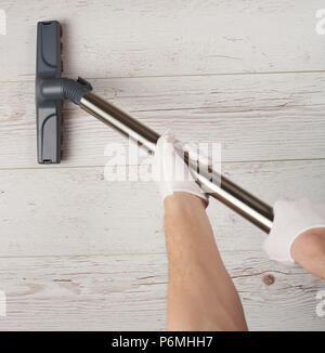 Plancher en bois nettoyage close up. Aspirateur sur les mains au-dessus de l'homme view Banque D'Images