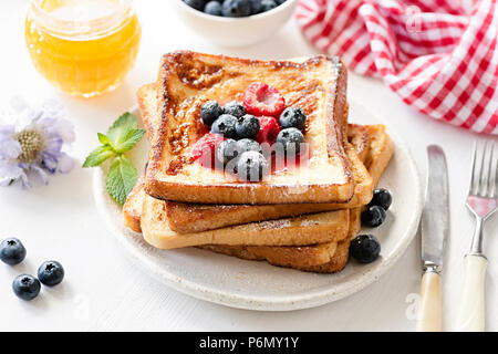 Délicieux pain perdu aux fruits rouges et miel sur plaque blanche. Petit-déjeuner savoureux concept Banque D'Images