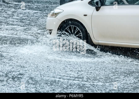 City Road en cas de mauvais temps. L'eau de pluie à partir de la pulvérisation de roues de voiture Banque D'Images