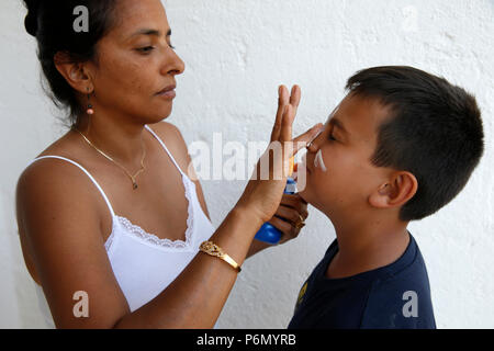 Mother putting crème solaire sur le visage de son fils dans le Salento, en Italie. Banque D'Images