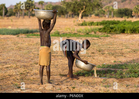 Les enfants togolais portant de l'eau pour l'irrigation en Karsome, Togo. Banque D'Images