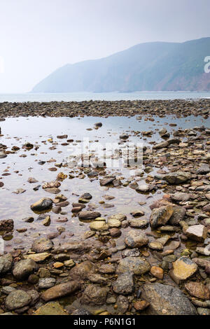 La plage rocheuse à Lynmouth, North Devon, avec réflexion et de voir l'avant-pays nord-est en direction de Point. Banque D'Images