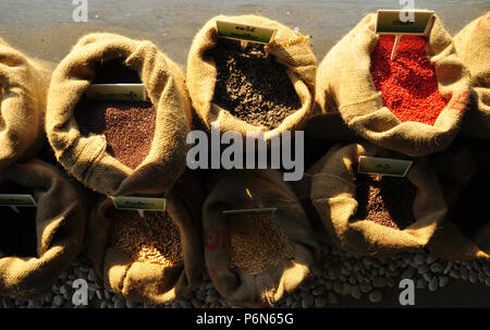 Graines de moutarde, de lin, de tournesol et de coriandre sont déversées à partir de sacs de linge Banque D'Images