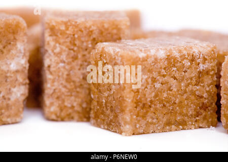 Cubes de sucre brun sur fond blanc. Banque D'Images