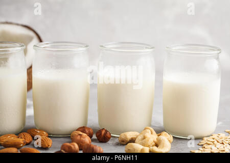 Écrou de rechange végétalien lait dans des bouteilles en verre sur un fond gris. La nourriture végétalienne saine concept. Banque D'Images