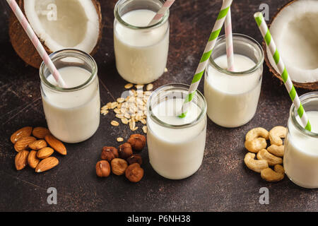 Écrou de rechange végétalien lait dans des bouteilles en verre sur fond sombre. Fond d'aliments sains. La nourriture végétalienne saine concept. Banque D'Images