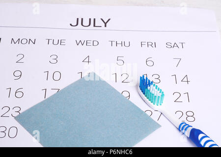 Calendrier avec une date marquée et brosse à dents pour rappeler aux rendez-vous chez le dentiste jour en juillet. En bonne santé et hygiène dentaire concept. Banque D'Images