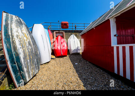 Cabane de plage Multi coloré et des barques stockées contre seawall à Thorpe Bay, Southend on Sea, Essex, Royaume-Uni. Le bois peint beach hut. Dériveurs Banque D'Images