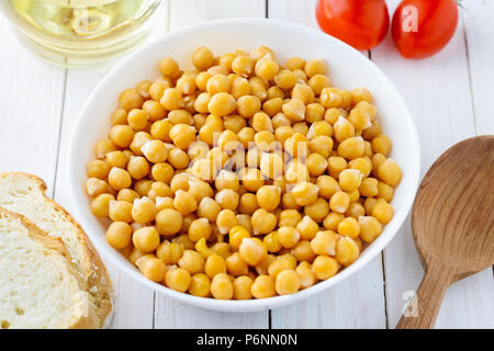 Pois chiches cuits dans un bol, de tomates et d'huile d'olive sur une table en bois. Savoureuse, saine alimentation végétarienne Banque D'Images