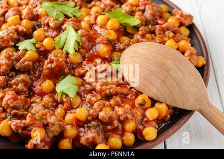 Une cuisine traditionnelle. Chili mexicain avec pois chiches bi et cuillère en bois sur une table en bois Banque D'Images