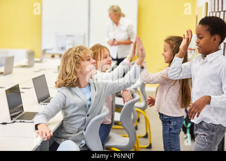 Les enfants dans l'école élémentaire l'école élémentaire se donner un cinq dans le cours en informatique Banque D'Images