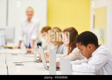 Groupe d'étudiants de l'école élémentaire de l'ordinateur en classe est l'apprentissage en ligne à l'ordinateur portable Banque D'Images