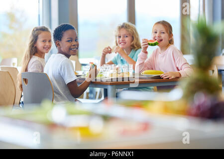 Groupe d'enfants comme des amis en train de déjeuner dans la cafétéria de l'école Banque D'Images