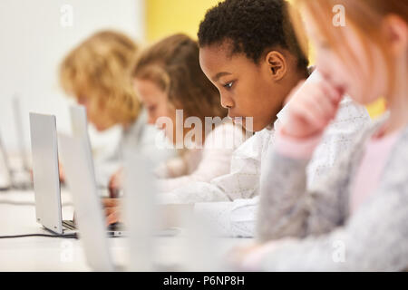 Groupe d'élèves dans une classe de l'école élémentaire de l'ordinateur est l'apprentissage avec l'ordinateur portable Banque D'Images