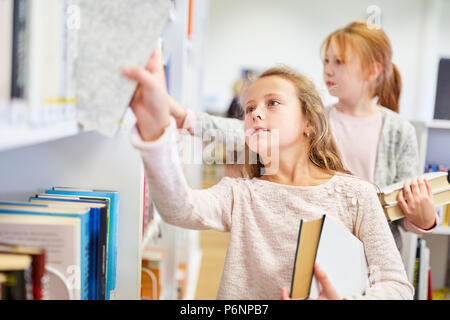 Girl en tant qu'étudiant à faire des recherches dans la bibliothèque de l'école élémentaire Banque D'Images