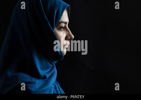 Belle jeune fille musulmane en hijab. Portrait d'une jeune femme arabe sur un fond noir. Banque D'Images