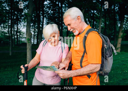 Couple de personnes âgées les randonneurs contrôle map in woods Banque D'Images