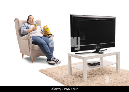 L'excès de femme avec un sac de chips et un verre assis dans un fauteuil et regarder la télévision isolé sur fond blanc Banque D'Images