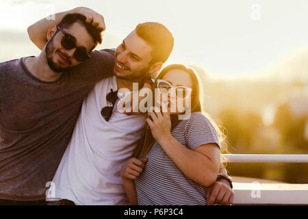 Photo de trois amis en posant sur le toit de l'immeuble au coucher du soleil Banque D'Images