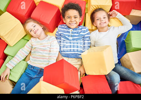 Trois enfants jouant dans la fosse de la mousse Banque D'Images