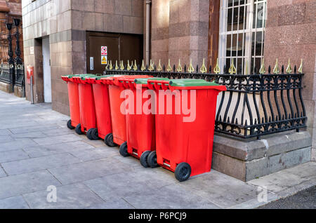 Une rangée de 6 rouge et 5 vert wheelie bins sur la chaussée dans une rue dans le centre-ville de Manchester, Royaume-Uni Banque D'Images