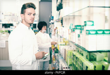 Les jeunes de l'équipe sérieuse et pharmaceutist technicien travaillant en pharmacie Banque D'Images