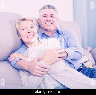 Heureux couple marié mature dans maison confortable sont chaleureusement réconciliée après querelle Banque D'Images