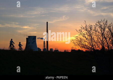 Coucher de soleil, ciel, ornage dans dusk tree, piste cyclable avec deux cyclistes, paretna et d'enfants, groupe de haut et grand, chimeys smkoe à partir de l'un d'eux Banque D'Images