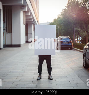 Young woman holding blank canvas sur la rue. Banque D'Images