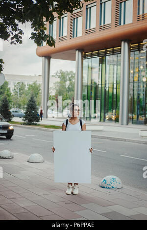 Young attractive woman holding blank canvas sur la rue et à côté. Banque D'Images