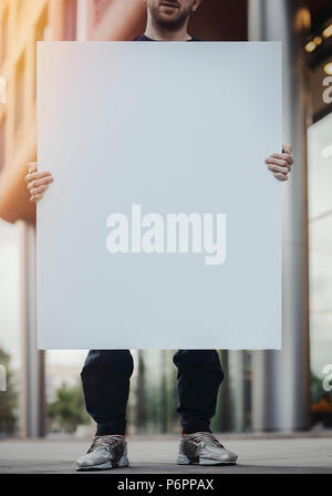Close up of young woman holding blank canvas sur la rue. Banque D'Images