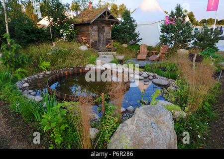 Londres, Royaume-Uni. 2e juillet 2018. Les croisières Viking jardin de vie nordique (conçu par Stephen Hall) L'un des beaux et élégants jardins afficher sur l'affichage à l'2018 RHS Hampton Court Flower Show qui s'est ouverte aujourd'hui dans le parc de Hampton Court Palace, Londres, Royaume Uni - 02 juillet 2018. Recréer un environnement boisé nordique, un chemin mène à pavée de pierre coin à côté d'un sauna traditionnel hut. Blocs de pierre nordique ensuite conduire à une piscine, bordée de galets et de petits rochers. Les grandes roches apparaissent à travers les zones de plus en plus d'herbe de prairie autour du sauna, tandis que les arbres et arbustes nordique Banque D'Images