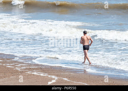 Skegness, Royaume-Uni, 2 juillet 2018. Un homme le jogging sur la plage utilise les vagues pour rester cool, comme la poursuite de temps chaud maintient des températures dans le Royaume-Uni à un niveau élevé. Crédit : Steven Booth/Alamy Live News. Banque D'Images