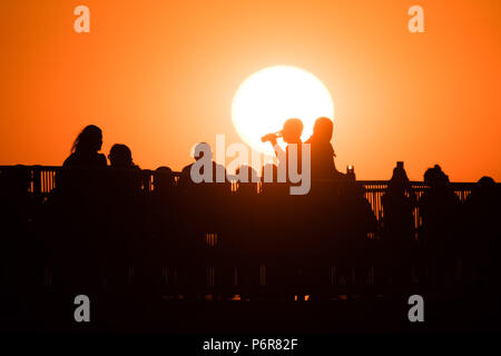 Aberystwyth, UK. 07 juillet, 2018. UK UK Weather : un magnifique coucher de soleil sur les personnes qui boivent sur la jetée à Aberystwyth à la fin d'une autre scorchingly chaud et serein, comme le jour de canicule prolongée continue à dominer la météo au Royaume-Uni. Crédit photo : Keith morris/Alamy Live News Banque D'Images