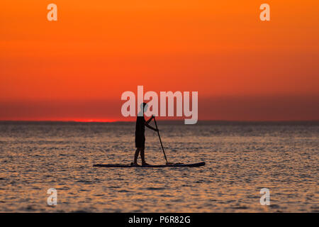 Aberystwyth, UK. 07 juillet, 2018. UK UK Weather : un glorieux coucher de silhouettes paddleboarders à Aberystwyth à la fin d'une autre scorchingly chaud et serein, comme le jour de canicule prolongée continue à dominer la météo au Royaume-Uni. Crédit photo : Keith morris/Alamy Live News Banque D'Images