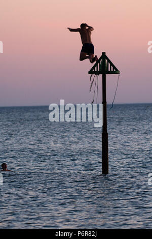 Aberystwyth, UK. 07 juillet, 2018. UK UK Weather:jeunes hommes sauter dans la mer fraîche à Aberystwyth à la fin d'une autre scorchingly chaud et serein, comme le jour de canicule prolongée continue à dominer la météo au Royaume-Uni. Crédit photo : Keith morris/Alamy Live News Banque D'Images