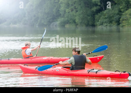 Père et fils, chaque palette un canot sur le lac de montagne Banque D'Images