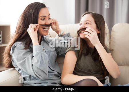 Deux soeurs jouant avec moustache sèche Banque D'Images