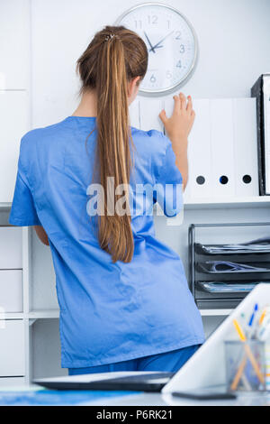 Jeune femme médecin assistant working in office, debout près de dossiers avec étagères Banque D'Images