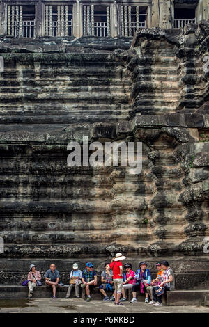 Les touristes asiatiques reste dans un cours à la base d'un temple de grès à Angkor Wat, Siem Reap, Cambodge. Banque D'Images