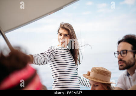 Jolie femme habillé en blouse dénudée sur parler avec les jeunes passagers luxueux yacht profiter de vacances d'imprudents et moment de paix à Banque D'Images